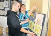 Klassenlehrerin Petra Freiwerth und Schüler Leon beim Aufhängen der Bilder im Schalterraum der Kreissparkasse Anhalt-Bitterfeld am vergangenen Freitag.